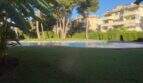 Piscina comunitaria con césped bien mantenido y jardín del complejo de áticos en Llucmajor, Mallorca.