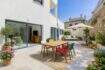 Terraza soleada con sillas de colores, mesa de madera y zona de estar en la casa urbana en Artà