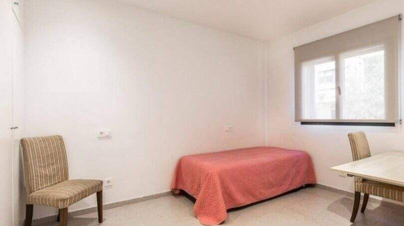 Helles Schlafzimmer mit Einzelbett, zwei Stühlen und Fenster im Stadthaus in Artà