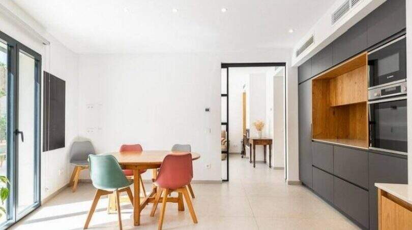 Helles Esszimmer mit bunten Stühlen und moderner Einbauküche im Stadthaus Artà