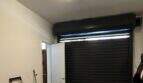 Garage mit schwarzem Rolltor, Seiteneingang, Deckenleuchte und Abstellfläche für Fahrräder in Artà.