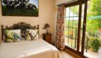 Schlafzimmer der Finca Llucmajor mit Eisenbett, Elefantenbild, Vogelkissen & Balkonzugang zum Garten