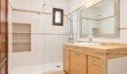 Helles Badezimmer mit Glasdusche, Marmor-Waschtisch und Holzunterschrank im Wohnhaus in Establiments, Mallorca.