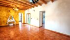 Amplio salón de la finca Inca con suelo de terracota, techo de vigas de madera y acento de pared amarillo