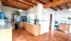 Amplia cocina de la finca Inca con techo de vigas de madera, armarios empotrados claros y suelo de terracota