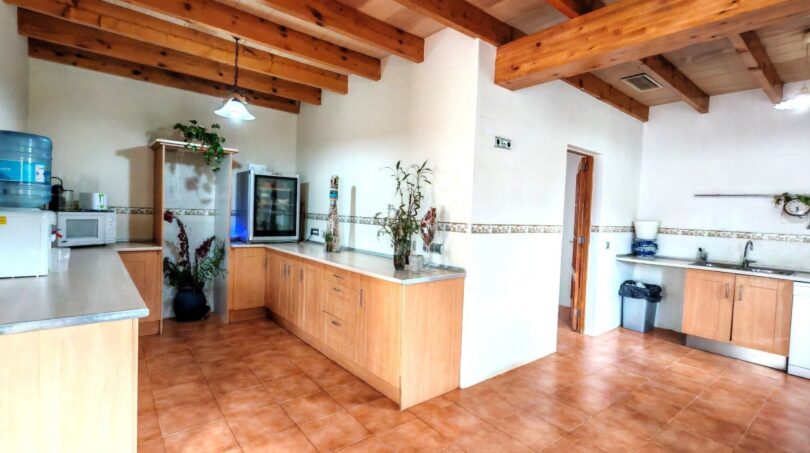 Amplia cocina de la finca Inca con techo de vigas de madera, armarios empotrados claros y suelo de terracota