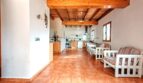 Área de salón-cocina abierta de la finca cerca de Inca con techo de vigas de madera, muebles blancos y suelo de terracota