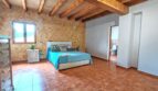 Amplio dormitorio de la finca Inca con techo de vigas de madera, suelo de terracota y baño privado