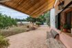 Terraza cubierta de la finca cerca de Inca con banco de madera, adoquines de barro y exuberante jardín con árboles frutales