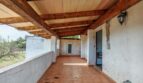 Terraza cubierta de la finca cerca de Inca con techo de vigas de madera, azulejos de terracota y vistas al verde