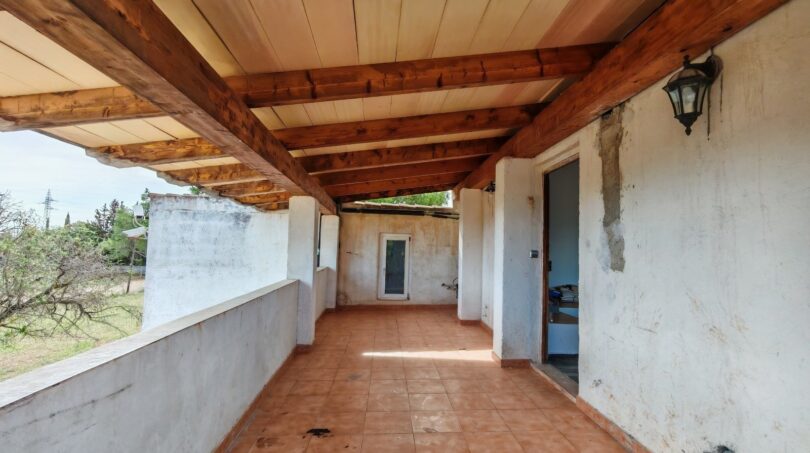 Terraza cubierta de la finca cerca de Inca con techo de vigas de madera, azulejos de terracota y vistas al verde