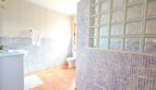Baño de la finca Inca con azulejos de mosaico, pared de ladrillos de vidrio, lavabo y suelo de terracota