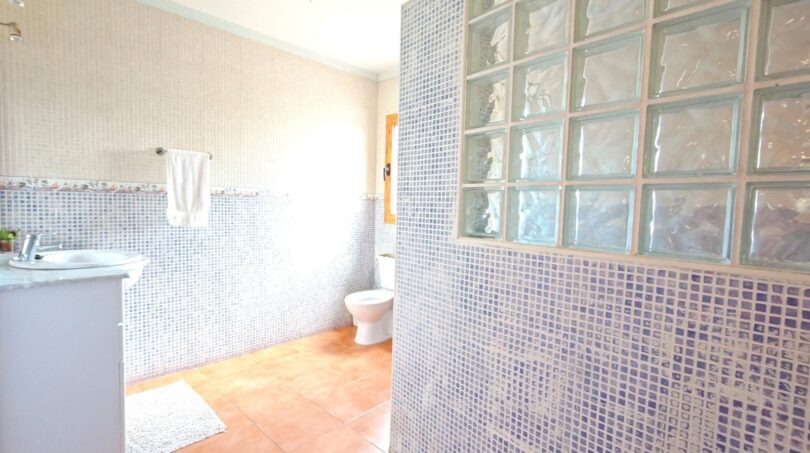Baño de la finca Inca con azulejos de mosaico, pared de ladrillos de vidrio, lavabo y suelo de terracota