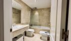 Elegante baño con azulejos de mármol, bañera con ducha, lavabo, WC y bidé en apartamento La Bonanova