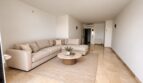 Luminoso salón con sofá L beige, mesa de mármol redonda y suelo de piedra natural en La Bonanova, Palma