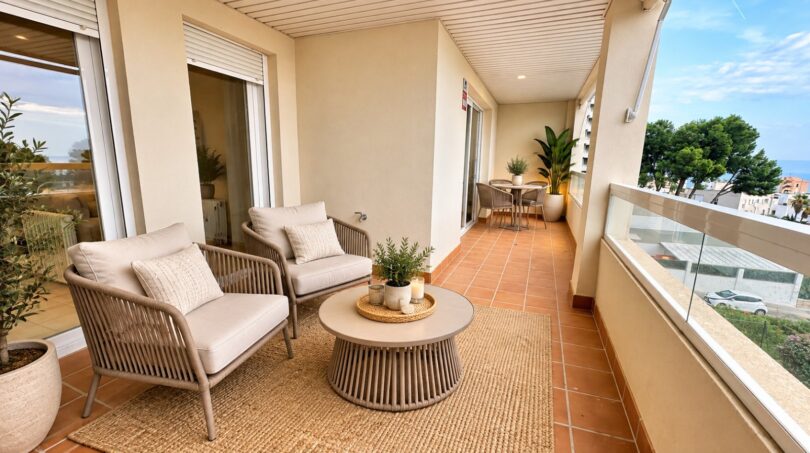 Terraza cubierta del apartamento en La Bonanova con muebles lounge, vistas al mar y ambiente mediterráneo.