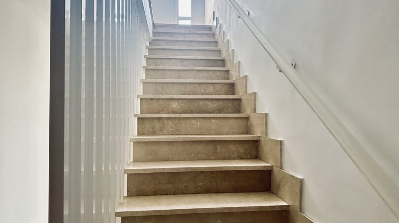 Luminosa escalera con tramo de mármol y barandilla de vidrio en amplio apartamento en La Bonanova, Palma