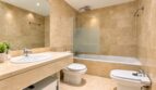 Badezimmer mit hochwertiger Natursteinausstattung und separater Wanne-Dusch-Zone