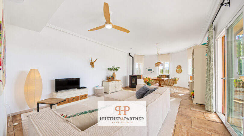 Helles Wohnzimmer mit Deckenventilator, Kaminofen, Essbereich und Terrassenzugang im Haus Cala Murada