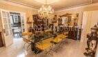 Elegantes Esszimmer der Villa in Marratxí mit Kristallleuchter, Glastisch und goldenen Stühlen.
