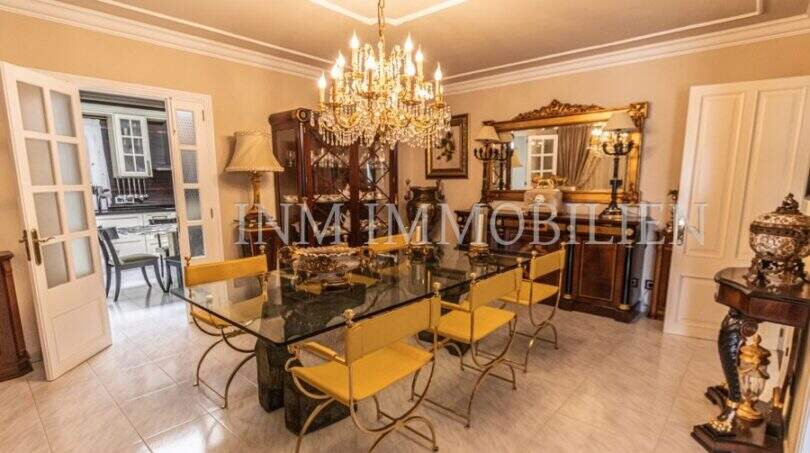 Elegantes Esszimmer der Villa in Marratxí mit Kristallleuchter, Glastisch und goldenen Stühlen.