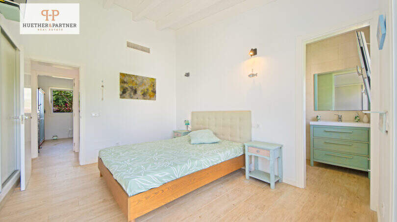 Helles Schlafzimmer mit Doppelbett, mintgrünen Akzenten und angrenzendem Bad im Ferienhaus nahe Es Trenc, Sa Ràpita.