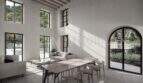 Zona de estar luminosa con techo alto, ventanas de arco de medio punto y vista al jardín mediterráneo de la finca en Sóller.