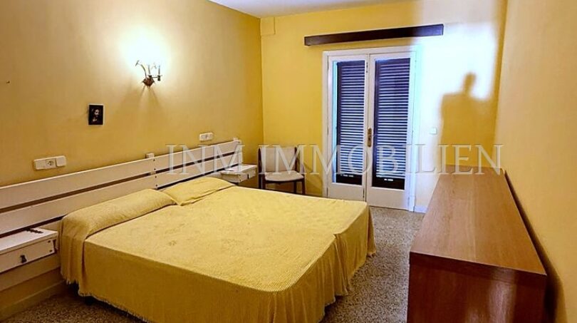 Helles Schlafzimmer mit Doppelbett, gelbem Wandanstrich und Balkonzugang in Meerlinie-Wohnung El Arenal
