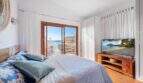 Dormitorio luminoso con cama doble, balcón con vista al mar y TV en villa mediterránea en Alcanada