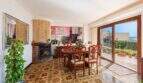 Sala de estar con chimenea, comedor, suelo de azulejos estampados y acceso a terraza con vista al mar en villa mediterránea