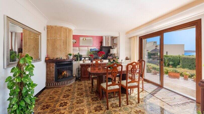 Sala de estar con chimenea, comedor, suelo de azulejos estampados y acceso a terraza con vista al mar en villa mediterránea