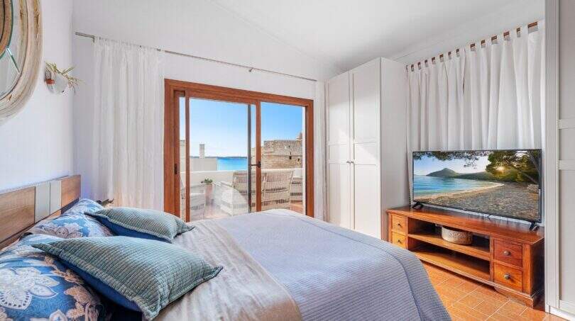Dormitorio de villa mediterránea en Alcúdia con cama doble, muebles de madera y balcón con vista al mar