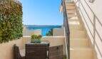 Terraza con muebles de ratán, escaleras y vista al mar azul turquesa de villa mediterránea en Alcanada