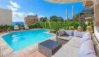 Área exterior de villa mediterránea en Alcúdia con piscina, muebles lounge, torre de vigilancia histórica y vista al mar