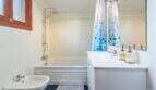 Baño luminoso de villa mediterránea en Alcanada con bañera, ducha de lluvia y cortina de ducha azul.