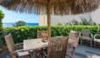 Terraza soleada con muebles de madera, techo de paja y vista al mar de villa mediterránea en Alcanada