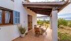 Covered terrace of the finca with wooden beams, dining table and view of the landscape of Colònia de Sant Pere