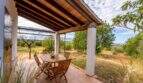 Covered terrace of the finca with wooden beams, dining table and view of nature and sea in Colònia de Sant Pere
