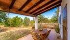Covered terrace of the finca with wooden beams, seating group and view of the natural garden.