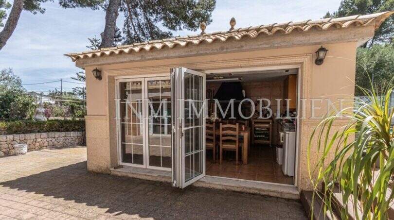 Überdachter Außenbereich der Villa in Marratxí mit Falttüren, Essbereich und mediterranem Ziegeldach.