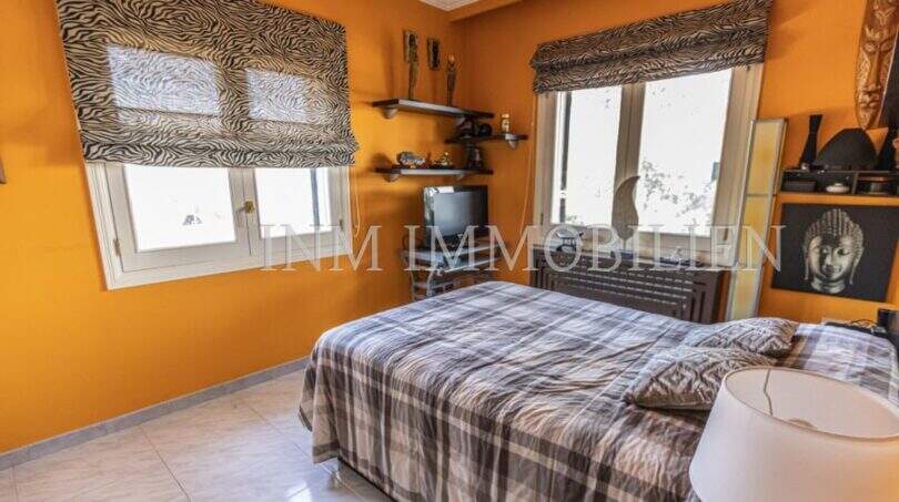 Schlafzimmer der Villa in Marratxí mit orangefarbenen Wänden, Doppelbett und Zebra-Jalousien an zwei Fenstern.
