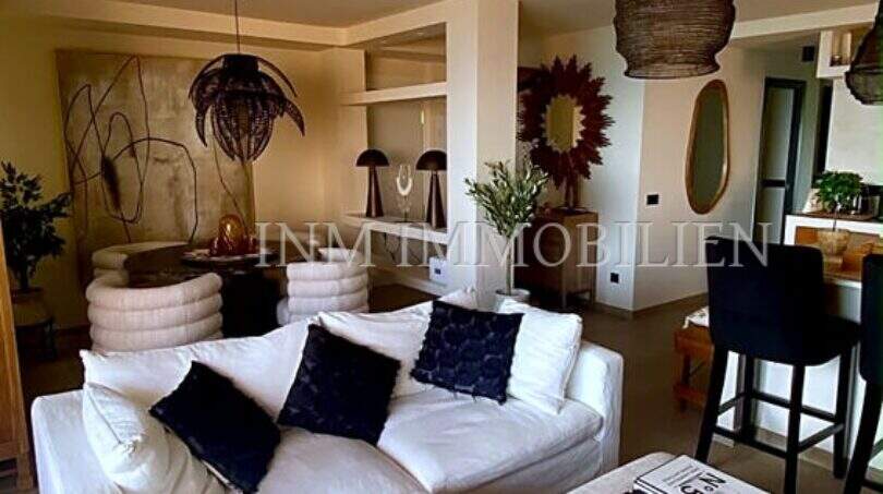 Helles Wohnzimmer mit weißem Sofa, dunklen Akzentkissen und stilvollen Rattanlampen im Penthouse Playa de Palma