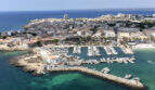 Luftaufnahme von Colonia de Sant Jordi mit Jachthafen, türkisblauem Meer und Stadtblick.