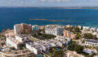 Luftaufnahme von Colonia de Sant Jordi mit weißen Apartments, Palmen und türkisblauem Mittelmeer im Hintergrund.