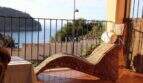Sonnenterrasse mit Korbliege und Meerblick auf die Bucht von Port de Sóller mit Leuchtturm