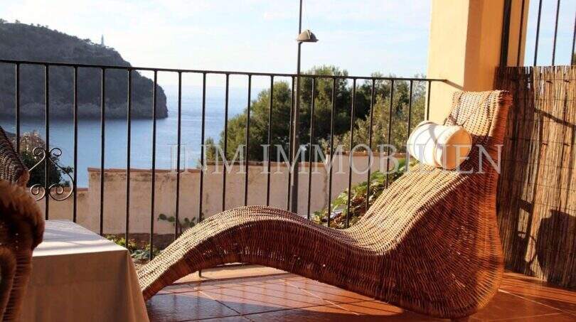 Sonnenterrasse mit Korbliege und Meerblick auf die Bucht von Port de Sóller mit Leuchtturm