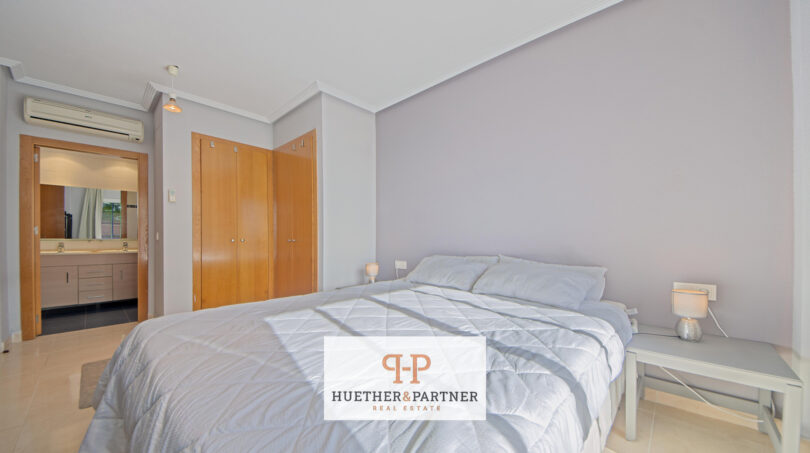 Helles Schlafzimmer der Mallorca-Wohnung mit Doppelbett, Einbauschrank und angrenzendem Badezimmer