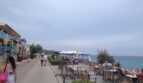 Strandpromenade in Cala Ratjada mit Cafés, Meerblick und türkisblauem Wasser direkt am Hafen.