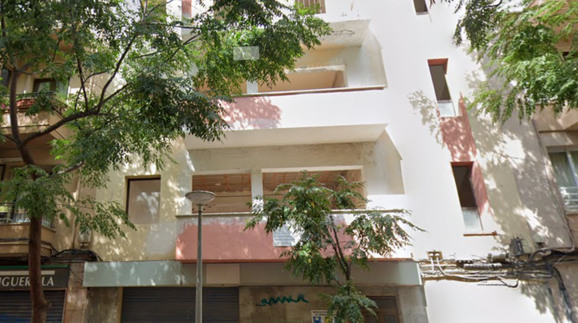 Vista exterior de un edificio residencial de varios pisos en Palma de Mallorca con balcones, fachada blanca y árboles.
