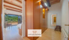 Área de vestidor con armario empotrado de madera, techo de vigas de madera y vistas al dormitorio luminoso con vistas a la montaña.